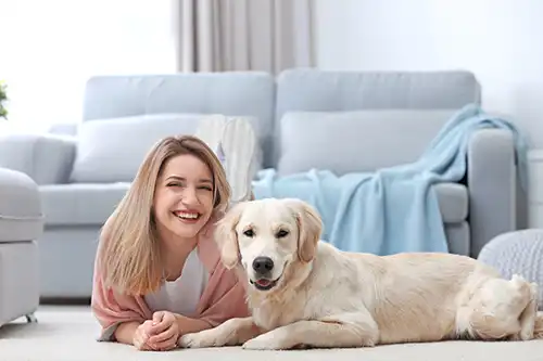 Sho-Me Flooring—A happy female homeowner laying on the carpeted floor with her dog in Branson, MO.